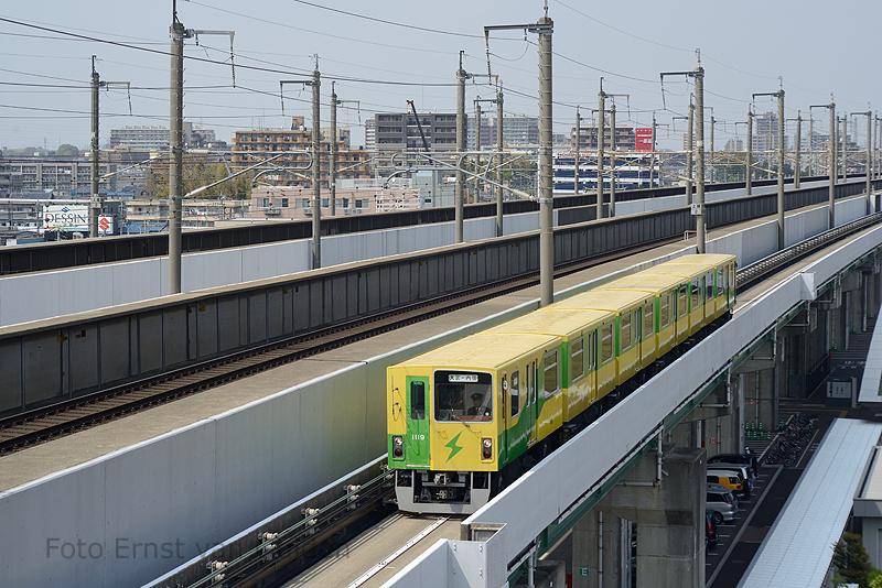 De New Shuttle is een automated guideway transit (AGT) systeem (met bestuurder) op rubber banden. De 12,7 km lange lijn loopt in het noorden van Tokio tussen de stations Ōmiya en Uchijuku. En wordt geëxploiteerd door de Saitama New Urban Transit Co., Ltd Hier zien we een series 1010 het station Tetsudō-Hakubutsukan (Spoorwegmuseum) naderen. De lijn loopt voor een deel (links) naast de Jōetsu Shinkansen richting Noord-Japan.De foto is genomen vanaf het dak van het spoorwegmuseum, dat (schuin)onder de beide spoorlijnen ligt.