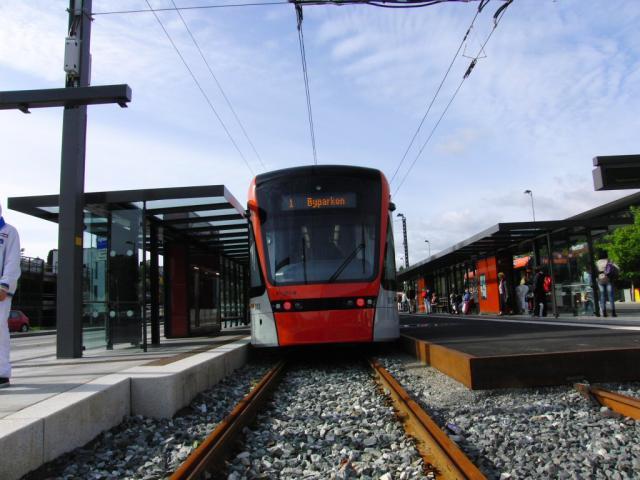 De eerste tramlijn van de Bergen Bybanen sinds lange tijd is net nieuw (geopend op 22 juni 2010). We rijden de hele 9,8 km lange lijn met max. 70 km/u heen en terug langs lachwekkende haltes, zoals Sletten en Slettenbakken. Daarbij reizen we met een chipkaart waarmee we eerst moeten innsjekken.Let op het bord links op de foto, dat het andere verkeer moet waarschuwen voor de komst van dit nieuwe… railvoertuig.De mooie moderne voertuigen (al met enkele vierkante wielen) zijn normaalsporig, zodat ze gedeeltelijk over het hoofdspoornet hierheen hebben kunnen komen.Foto: Theo Gramser Periode: juli 2010