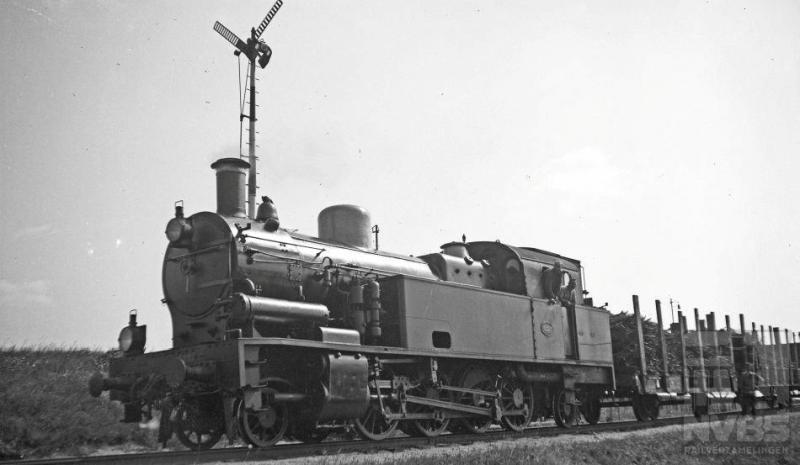 Bij de rangeerheuvel op het Amersfoortse emplacement zien we 1D1-loc 6227 met een aantal rongenwagens staan. Let ook op het heuvelsein: het staat in de stand “heuvelen toegestaan” zodat we mogen aannemen dat het heuvelen al is begonnen. Dit type tenderlocomotief kwam vanaf 1912 bij de Staatsspoorwegen in dienst om de zware kolentreinen uit Zuid-Limburg te trekken. Met hun 10.700 kg trekkracht voldeden zij uitstekend. Hohenzollern uit Düsseldorf heeft ze gebouwd in een serie van veertig stuks (NS 6201-6240). 10 augustus 1935.