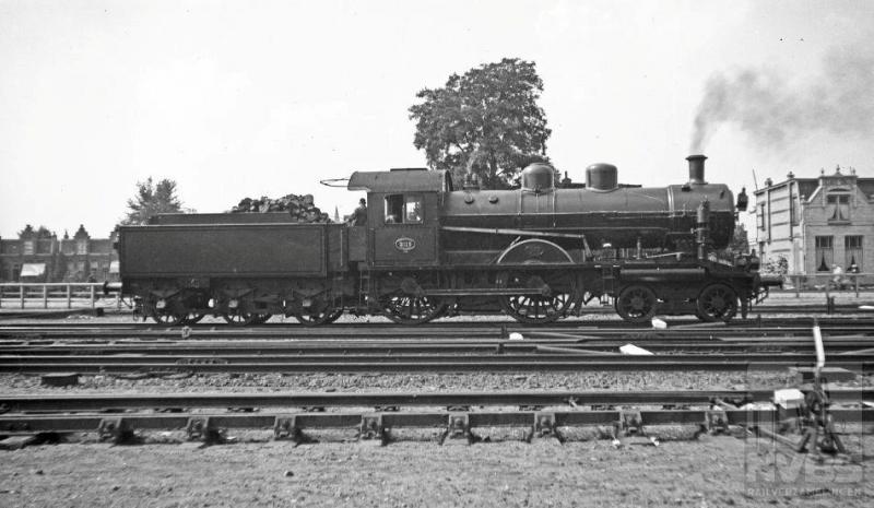 Tussen de voorlopers van de NS is er altijd sprake geweest van concurrentie. Vooral tussen de twee grote: HSM en SS. De serie 2B-locomotieven 501-535 was in 1914 het antwoord van de HSM op de een paar jaar eerder bij de SS in dienst gestelde 2C-machines, de latere 3700-en bij de NS. De HSM-locs waren wel wat lichter, maar door hun constructie met binnenliggende cilinders en enorme drijfwielen -2100mm in doorsnee-, uitstekend in staat snelle prestaties te leveren. Bij de NS kreeg de serie de nummers 2101-2135. Had de keuze van deze nummering soms iets te maken met eerdergenoemde wieldiameter? Op de foto staat de 2115 onder stoom op het emplacement, maar wat zij ging doen kunnen we van de foto niet aflezen. Hesselink maakte deze plaat op dezelfde dag als de vorige: 10 augustus 1935.