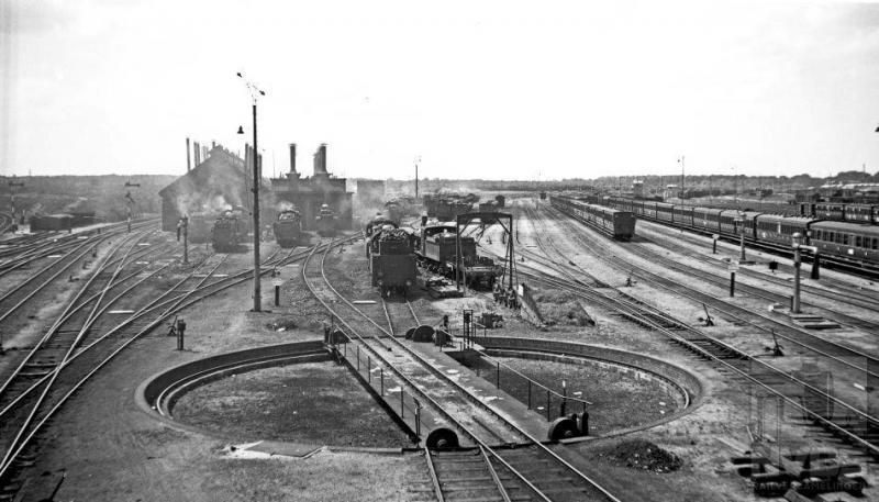 Deze foto geeft een goed overzicht van het gigantische emplacement van station Amersfoort, zoals het er op 5 juli 1936 bij stond. Vooraan de draaischijf en meer naar achteren locomotieven onder stoom voor de loods. Rechts rijen met treeplankrijtuigen.