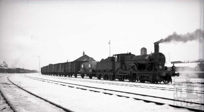 “Vroeger hadden we tenminste nog echte winters”: op Tweede Kerstdag 1938 zien wij een 1700-er met een goederentrein het emplacement van Amersfoort verlaten voor een tocht in een witte en stille wereld. Het betreft hier een locomotief uit de grootste serie van de NS, namelijk NS 1700-1835 (135 stuks ). Er zijn verschillende subseries te onderscheiden, de meeste afkomstig uit Engeland terwijl een tiental machines door Werkspoor zijn gebouwd. Aan de grote drijfwielen is te zien dat zij -aan het eind van de 19e eeuw- ontworpen zijn om sneltreinen te trekken. In de dertiger jaren echter waren er voor dit doel al sterkere locs bij de NS aanwezig waardoor de 1700-en degradeerden tot trekkracht voor lokaal- en goederentreinen.