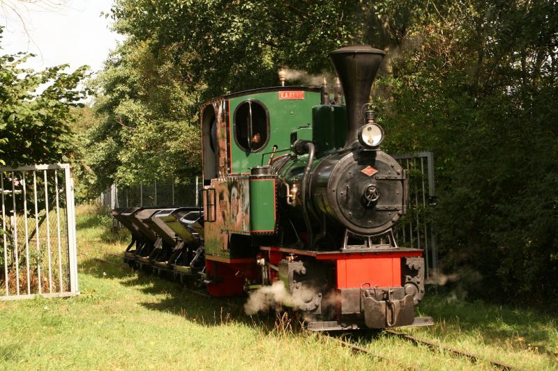 31 augustus 2013Twee stoomlocs zijn op de open dag continu in bedrijf. Ze rijden solo of achter elkaar een (driekwart) rondje om het Valkenburgse Meer, lopen aan het eindpunt om en keren terug, dan wel met vier rijtuigen aan de haak, dan wel met enkele kiepkarretjes. Loc 4 (K.A. Neve - O&K), waagt zich in de ochtend even buiten de poort van het stationsemplacement.