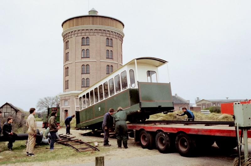Loc 4 wordt met behulp van een dieselloc op een dieplader gereden.Hetzelfde gebeurt met een zelfgebouwd rijtuig, dat tegenwoordig voorzien is van latjes, waardoor het er ouder uitziet.