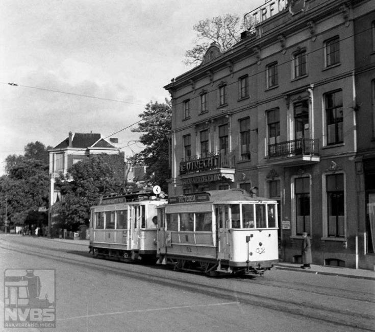 Bij het Arnhemse spoorstation, om precies te zijn in de Utrechtse straat, zien we een tramstel van lijn 4. Op deze lijn rijden niet de nieuwste vierassige motorwagens maar oudere uit de begintijd. Motorwagen 16 dateert uit 1912 en is op dit moment, 22 mei 1944, dus al 32 jaar oud. Maar in de oorlog moest alles wat rijden kon dit ook doen. Aanhanger 52 is nog veel ouder en afkomstig van de Arnhemsche Tramweg Maatschappij, de voorloper van de Gemeentelijke Electrische Tram Arnhem (GETA). Deze exploiteerde vanaf 1880 paardentramlijnen in Arnhem en Velp en de 52 is uit de begintijd van déze maatschappij. Door hevige gevechtshandelingen moest het trambedrijf op 17 september 1944 worden stilgelegd. Er was te veel verwoest aan materieel en infrastructuur om de dienst na de oorlog te hervatten. Gelukkig rijden er nog altijd trolleybussen.Foto: J.A.Bonthuis (129.054C)