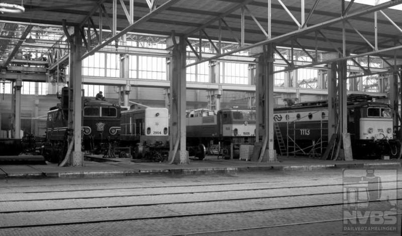 Tot slot nog een plaatje uit Tilburg, waar we in een van de hallen de elektrische locomotieven 1154, 1505 en 1113 plus diesellocomotief 2904 zien staan. Deze laatste was afkomstig van de Staatsmijnen, in de vijftiger jaren door Henschel gebouwd. De serie 2901-2905 heeft maar vijf jaar bij NS dienst gedaan, tot 1975. Hun derde leven gingen zij leiden in Spanje. 17 april 1974 (J.A.Bonthuis; 509.693C).