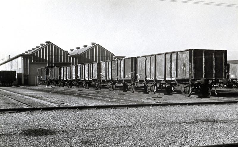 Een rij kolenwagens staat te wachten. Aan dit type wagens had men veel werk omdat ze niet zachtzinnig werden behandeld. Kolenwagens waren nog volop in gebruik voor he transport van de Limburgse kolenmijnen naar de rest vanhet land. Waarschijnlijk is de foto genomen in Blerick waar een dependance van Amersfoort was, en waar veel kolenwagens werden opgeknapt.