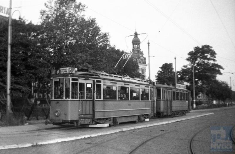 Zonder enig vlagvertoon of versiering reed vanaf 18 juni in Amsterdam lijn 16 weer. We zien hier motorwagen 405 met aanhangwagen 790 op de Prins Hendrikkade op deze eerste dag. De tweeassers zouden nog geruime tijd dienst blijven doen in de hoofdstad, tot in de vijftiger jaren. In 1948 kwamen de drieassers en pas in 1957 de eerste vierassers -van Beijnes- op de rails. (foto L.J.A.M. Heijmeijer 131.001; 18-6-1945)