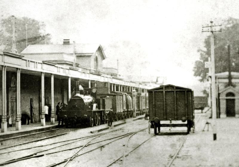 De enige foto uit de tijd dat de HSM (Hollandsche IJzeren Spoorweg-Maatschappij) nog op breedspoor reed. Afgebeeld is het station van Haarlem, ca 1865. De loc is de HOLLAND (gebouwd bij R. Stephenson in 1856).