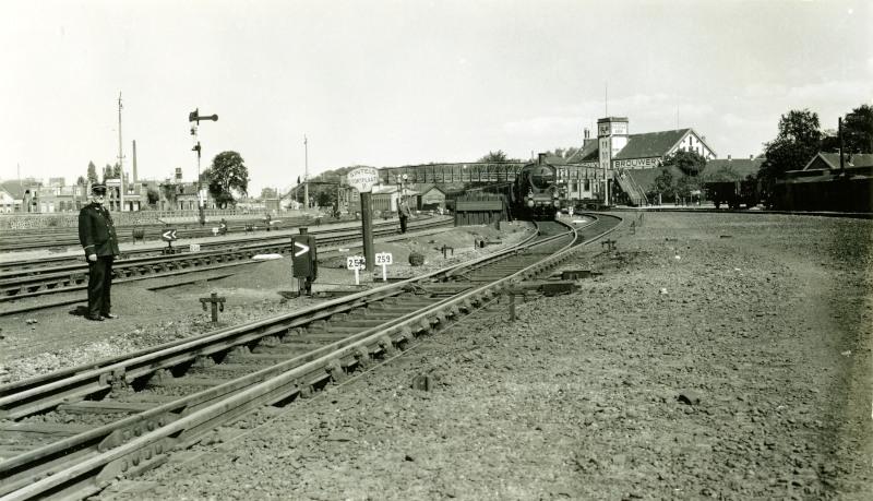 Op deze foto kijken we in omgekeerde richting vanaf het station van Amersfoort naar het oosten. Deze foto is gemaakt in 1940. We zien in het midden het bord "Sintels Stortplaats II". Hier werd de as uit de stoomlocomotieven gestort; even verderop staat loc 3725 kolen te laden. Langs het spoor zijn de trekdraden te zien waarmee vanuit een seinhuis de wissels en armseinen werden bediend.De loopbrug in de verte en de Phoenix brouwerij zijn allang verdwenen, maar vlak naast het eerder genoemde bord is nog net het eerste station van Amersfoort te zien (het witte gebouw); dit gebouw staat er nog steeds.