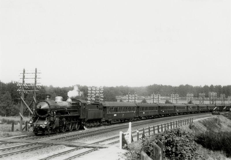 Trein met stoomloc uit de serie 3600 (dit type stond bekend als "Zeppelin") onderweg te Oosterbeek-Laag. De trein is de Nederland Expres, die te Marseille aansluiting gaf op de boot naar Indië, waardoor die reis vanuit Nederland met enkele dagen werd bekort. De wagons zijn van Wagons-Lits (CIWL, of Compagnie Internationale des Wagons-Lits et des Grands Express Europeens).Langs de lijn zijn de telegraafdraden te zien die nodig waren voor de communicatie tussen de stations. Overal langs de hoofdspoorlijnen zag men dergelijke telegraafpalen, alleen meestal niet met zoveel draden eraan als in dit geval.