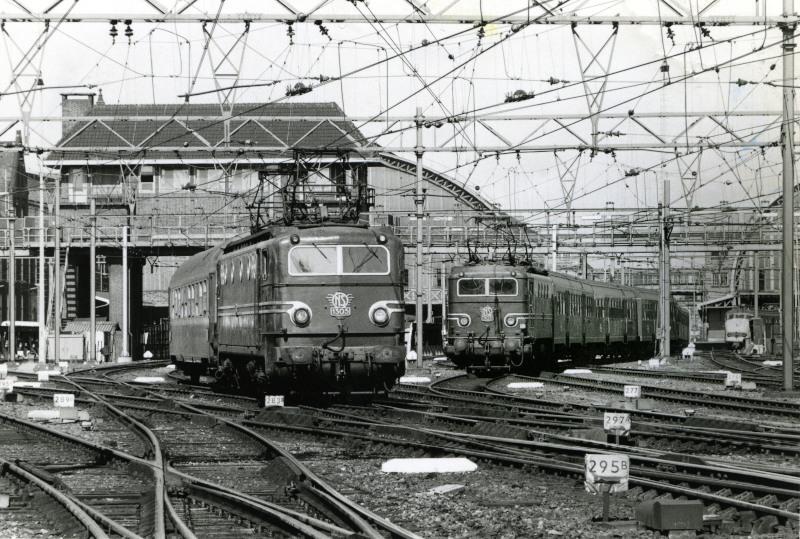 Amsterdam CS met twee treinen, links een internationale (nacht)trein met slaaprijtuig, richting Arnhem of het opstelterrein Dijksgracht, rechts een sneltrein naar Enschede met rijtuigen Plan W.Boven de treinen is het seinhuis te zien. Vanuit dit seinhuis werden seinen en wissels bediend.19 augustus 1974. Foto: Peter van der Vlist.