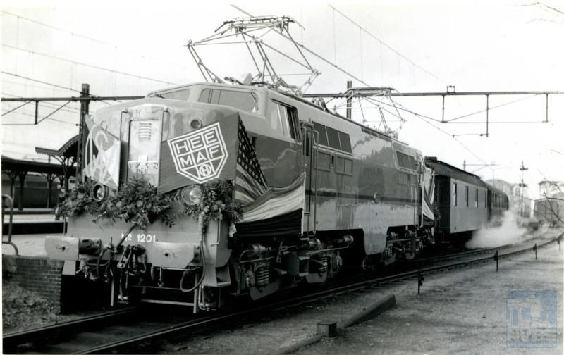 Loc 1201 kort na de aflevering. De serie 1200 is gebouwd door Werkspoor met een electrische installatie van Heemaf, naar een Amerikaans ontwerp. Van deze serie zijn nog enkele exemplaren af en toe in gebruik, een bewijs van de grote degelijkheid van deze locs.Achter de loc een van DB gehuurde verwarmings­wagen. Verwarmings­wagens waren nodig omdat de personen­rijtuigen nog waren ingericht voor stoomverwarming. Bij gebrek aan een stoomlocomotief gebruikte men een verwarmingswagen.De foto is gemaakt op 27 november 1951 bij vertrek uit Utrecht voor een speciale rit met het Koninklijk Instituut van Ingenieurs (KIVI).