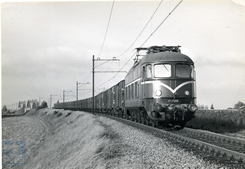Diemen; op de achtergrond de bruggen over de weg en over de Diemer Trekvaart.NS-loc 1008 trekt een trein van "geelbanders", stukgoedwagens metvervoer voor Van Gend & Loos.