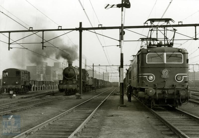 Goederentreinen te Heerlen. Naast elkaar rangeerloc 645, stoomloc 4731 met een kolentrein, en elektrische loc 1125 met erachter een loc serie 1200.