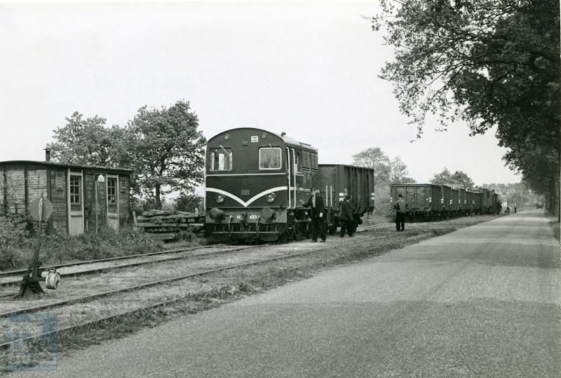 Makkinga is een plaats aan het uitgestrekte net van de NTM (Nederlandse Tramweg-Maatschappij). In de tijd dat deze foto is gemaakt, reden er al geen personentrams meer (personendienst gestopt in 1947), maar er kwamen nog wel goederentreinen van de NS. De tramlocomotieven serie 451-460 werden door Werkspoor gebouwd voor de vroegere stoomtramlijnen van de N.T.M. en W.S.M., waar NS nog een aantal jaren de goederendienst exploiteerde.Links naast de trein is een goederenwagen afkomstig van de N.T.M. te zien, die dient als personeelsverblijf.Foto J.G.C. van de Meene.