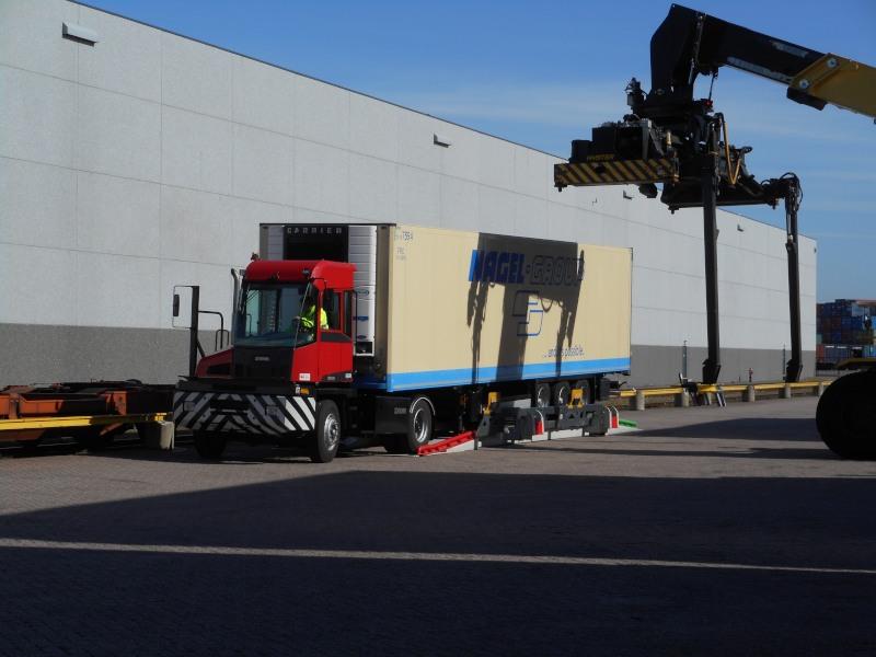 Begin van de demonstratie; een trekkertje heeft de oplegger op een speciaal platform gereden en de hijskraan komt aanrijden. 2 van de 4 z.g. lepels zijn al uitgeklapt.