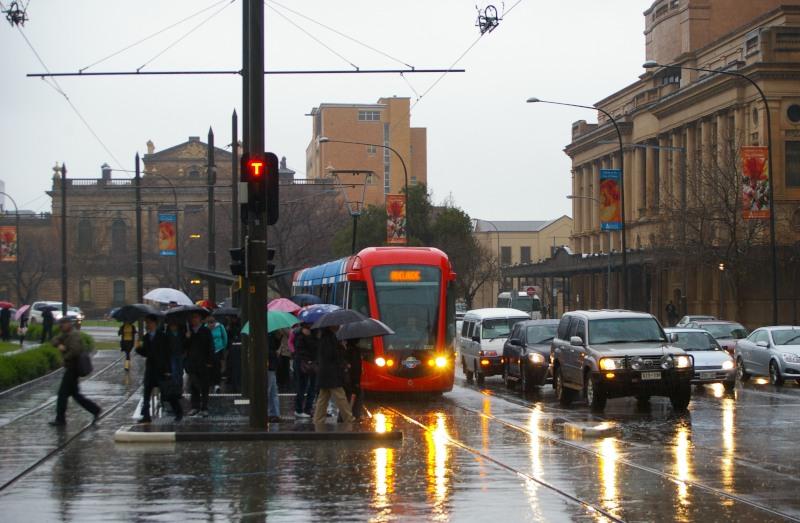 Niet zo′n typisch Australisch plaatje. Zuid-Australië staat bekend als de droogste staat op het droogste continent ter wereld. Een plaatje in de regen is alhier een beetje bijzonder. Citadis 202 op het Victoria Square, Augustus 2007.Het eindpunt "Entertainment Centre′ is ruim, en vooral zwaar uitgevoerd. De parkeergarage van het Entertainment Centre dat gedurende de dag niet gebruikt wordt, biedt gedurende die tijd goedkoop parkeren aan, $ 4.00 per dag inclusief tramrit naar de binnenstad vv.Het eindpunt in Glenelg bij het strand is daarentegen met een enkel kopspoor beperkt in capaciteit en is een flessehals gedurende drukte en vertraging. Gedurende de zomermaanden wordt veel van de tram gebruik gemaakt voor een dagje strand.
