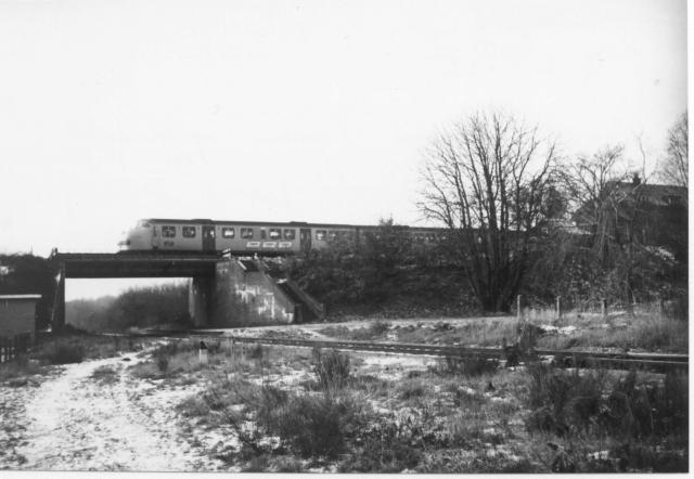 DE3-trein Roermond - Nijmegen op het viaduct over de voormalige NBDS-lijn Boxtel - Gennep. Station Beugen hoog is nog aanwezig, evenals de trap langs het viaduct die beide stations met elkaar verbond.Foto: foto 5179.063 B Periode: 26 december 1970