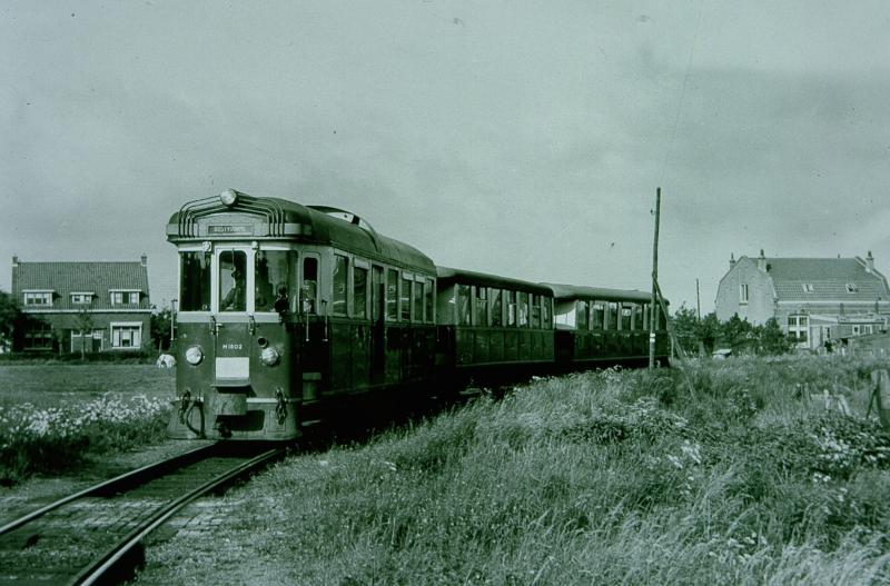 Tram in de bocht voor het station van Oostvoorne. De tram wordt getrokken door de M1802, genaamd ′Zwaluw′. De eerder genoemde H.W. Tap heeft de kop van deze motorwagen ontworpen.