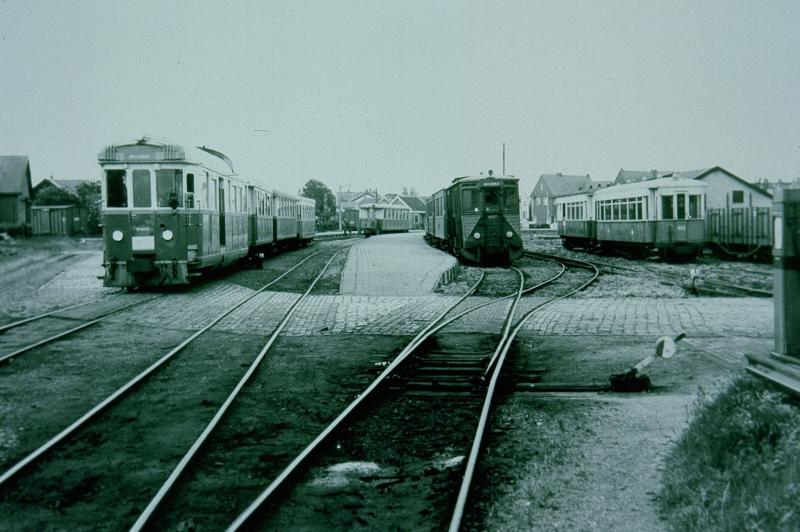 We zijn aangekomen in het station van Oostvoorne. De meeste trams eindigen hier, en er is een uitgebreid emplacement. De foto geeft ook een indruk van de veelvormigheid van het RTM-materieel. Links staat de M1802, een voormalig benzinemotorrijtuig, dat begin jaren ′50 verbouwd is tot diesel-mechanisch rijtuig; rechts daarvan de M67, en geheel rechts staan enkele personenrijtuigen die van de NBM (Nederlandse Buurtspoorweg Maatschappij) afkomstig zijn.Foto: L.J.P. Albers, 8 juni 1958.