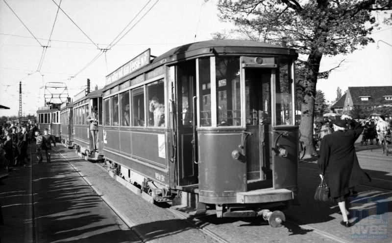 Op 2 mei 1949 viel het doek voor de NBM-lijn Utrecht-Zeist. J.A.Bonthuis heeft op deze laatste dag nog een aantal foto's gemaakt, waarvan dit er een is. U ziet dat de trolleystang inmiddels is vervangen door een schaarbeugel. Bij het station in Zeist staat motorwagen 12 met de aanhangrijtuigen 91, 96 en 94 gereed voor misschien wel de allerlaatste rit. Via deuren in de balkonschermen kon de conducteur zich van het ene naar het andere rijtuig begeven. (NVBS-fotonummer 130.630)