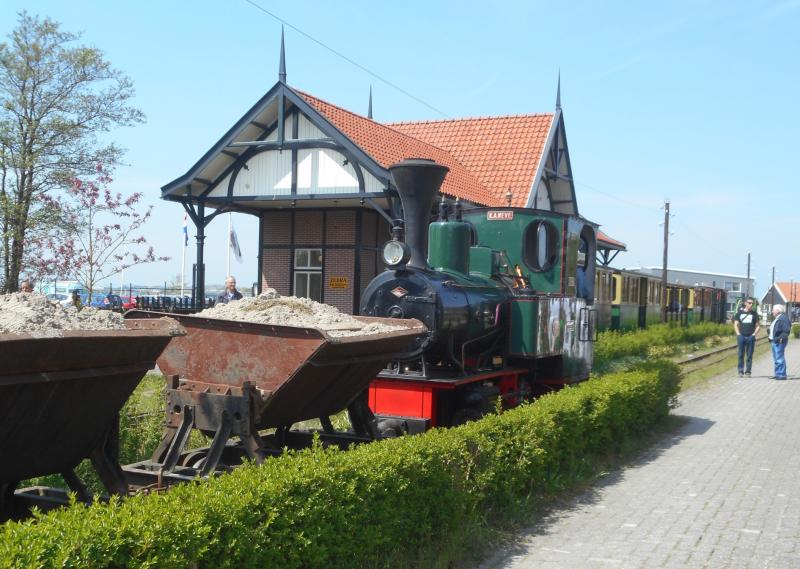 Aan de perronzijde staat het treintje al klaar, zij het nog zonder locomotief. Ernaast staat het zandtreintje dat na de personentrein zal vertrekken voor een rit langs het meer.