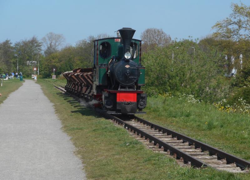 Na de personentrein volgt op enige afstand het zandtreintje, bestaande uit een stoomlocje en een sleep kipwagens. Veel aannemers en steenfabrieken gebruikten dergelijke treintjes om zand of klei te vervoeren.