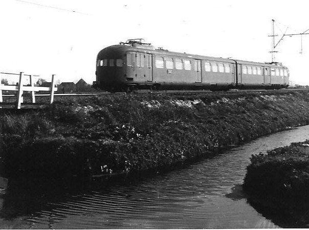 Vanaf 1935 komen de gestroomlijnde elektrische treinstellen in dienst, als eerste op de lijn van Rotterdam naar Hoek van Holland maar naarmate er meer door Beynes, Werkspoor en Allan werden gebouwd, ook op andere lijnen waaronder De Oude. Het tweetje op de foto, gefotografeerd in de buurt van Delft, is er een uit de eerste series met nummers tussen 201 en 263. Op de foto is het juiste nummer niet te zien. Later komen er ook drie-, vier- en vijfdelige op de baan. Dit type elektrisch treinstel is zeer succesvol gebleken: tot ver na het einde van de Tweede Wereldoorlog hebben ze op het NS-net dienst gedaan. Ir. W.R.G. van den Broek heeft de foto gemaakt op 10 oktober 1940 (NVBS-fotonummer 5385.0414).