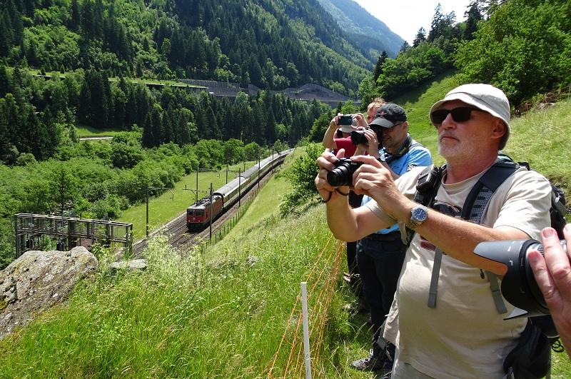 Op de foto houdt net ná de lunch een aantal wandelaars halt bij Gurtnellen aan de Gotthard-spoorlijn op 29 juni 2016 om een passerende Intercity van Lugano naar Zürich te fotograferen.