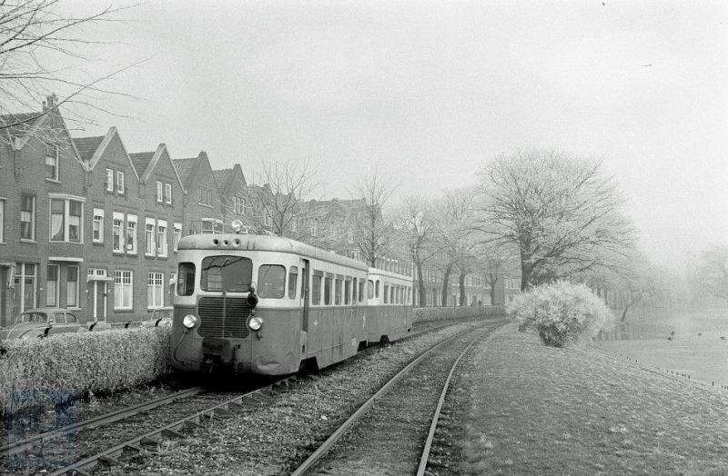 en RTM-motortramstel De Fuut - M2001 met bijbehorende bijwagen B2011 - spoedt zich op eigen baan langs de Boergoensevliet naar het Rotterdamse eindpunt aan de Rosestraat. Of komt hij juist daar vandaan? Foto: J.J. Overwater, 13-3-1958.