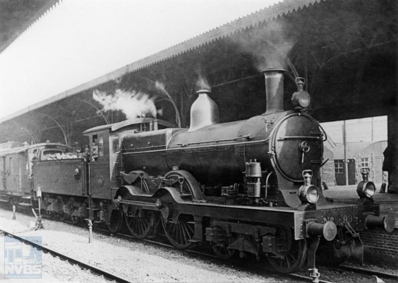 Aan een van de perrons van station Vlissingen staat locomotief 998 van de Staatsspoorwegen gereed. De bel aan de zijkant van de tender is met een koord verbonden met de bagagewagen achteraan, waar de hoofdconducteur vanuit zijn hooggelegen uitkijkkast belsignalen kon geven aan de machinist.