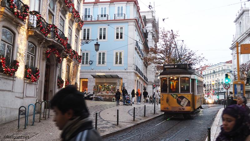 Wagen 578 van lijn 28E trekt vanaf de Taag omhoog door een feestelijk versierde straat.