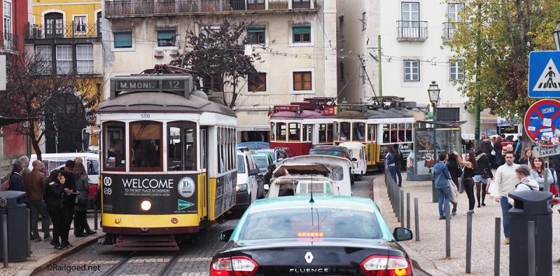 Halte Largo das Portas do Sol: drie trams, rijen auto's en massa's wandelaars. Wagen 580 rijdt voor lijn 12, wagen 559 voor lijn 28 en de rode wagen 8 voor een reisgezelschap.
